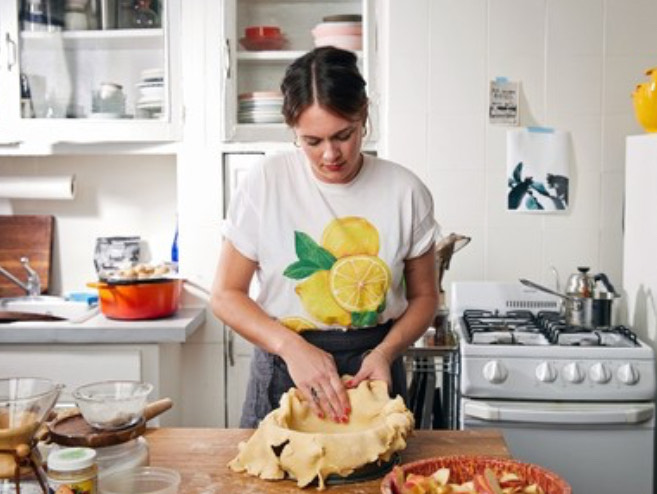 This is a picture of Alison Roman cooking in a white kitchen.